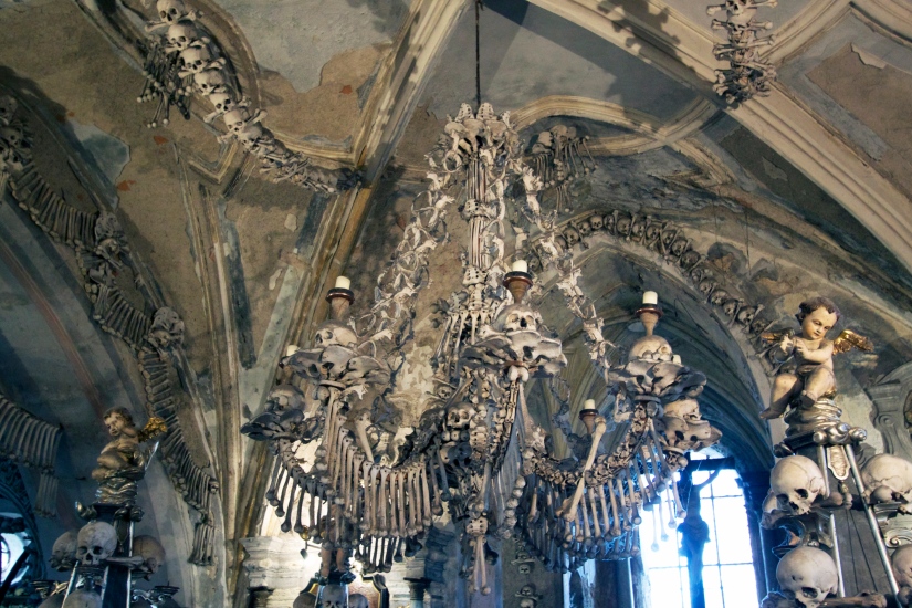 An enormous chandelier of bones, which contains at least one of every bone in the human body, hangs from the center of the nave with garlands of skulls draping the vault